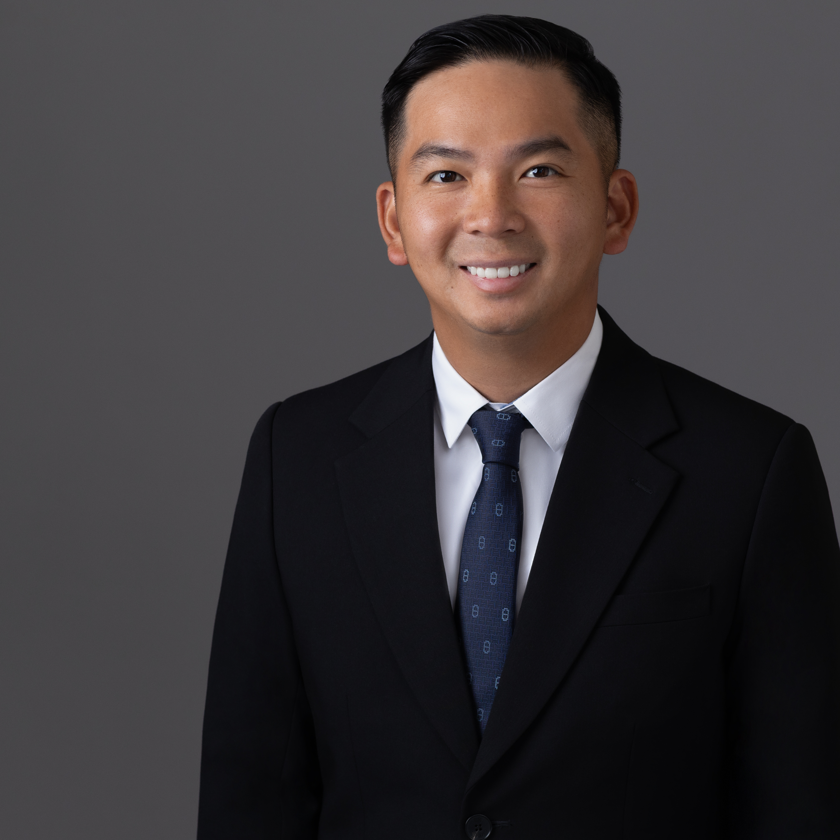 Quoc wearing a dark suit and blue tie